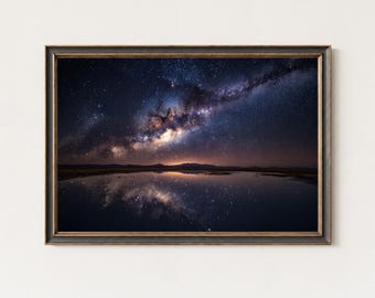 Peut inclure: Impression encadrée d'un ciel nocturne avec la Voie lactée se reflétant dans l'eau. L'image présente un ciel bleu foncé et violet rempli d'étoiles, avec une lueur dorée à l'horizon. Le cadre est marron foncé.
