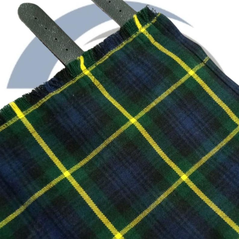 May include: Close-up of a traditional tartan kilt with a green, navy blue, and yellow plaid pattern. The kilt has a fringed edge and two dark gray leather straps.