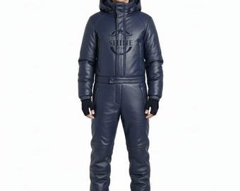 以下が含まれることがあります： ネイビーブルーのスキーウェア。フード付きジャケットとパンツがセットになっています。ジャケットには「SHINE」の文字とロゴが入っています。黒いビーニーと手袋を着用しています。スキーウェアは革のような素材で作られています。