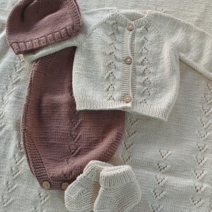 Handmade organic cotton knit baby outfit set including sweater, romper, booties, hat, and blanket. Made from 100% GOTS-certified organic cotton yarn, soft, breathable, and gentle on newborn skin. Available in multiple variations: hat and socks, hat socks cardigan, hat cardigan romper, or full 5-piece set. Custom color combinations available. Perfect for baby showers, coming-home outfits, or newborn photoshoots.