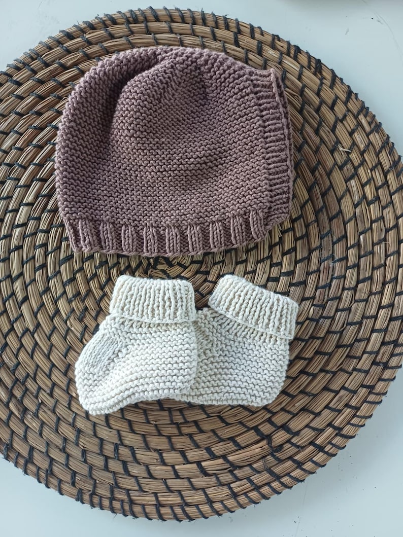 Handmade organic cotton knit baby outfit set including sweater, romper, booties, hat, and blanket. Made from 100% GOTS-certified organic cotton yarn, soft, breathable, and gentle on newborn skin. Available in multiple variations: hat and socks, hat socks cardigan, hat cardigan romper, or full 5-piece set. Custom color combinations available. Perfect for baby showers, coming-home outfits, or newborn photoshoots.
