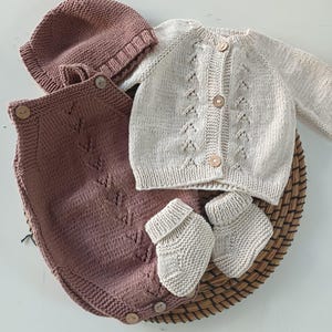 Handmade organic cotton knit baby outfit set including sweater, romper, booties, hat, and blanket. Made from 100% GOTS-certified organic cotton yarn, soft, breathable, and gentle on newborn skin. Available in multiple variations: hat and socks, hat socks cardigan, hat cardigan romper, or full 5-piece set. Custom color combinations available. Perfect for baby showers, coming-home outfits, or newborn photoshoots.