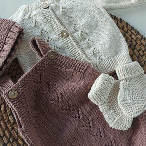 Handmade organic cotton knit baby outfit set including sweater, romper, booties, hat, and blanket. Made from 100% GOTS-certified organic cotton yarn, soft, breathable, and gentle on newborn skin. Available in multiple variations: hat and socks, hat socks cardigan, hat cardigan romper, or full 5-piece set. Custom color combinations available. Perfect for baby showers, coming-home outfits, or newborn photoshoots.