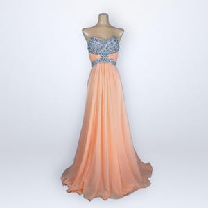 May include: A white ceramic mug with a black handle and the text "But First, Coffee" in a handwritten style. The mug is on a white surface. The mug is likely used for hot beverages.