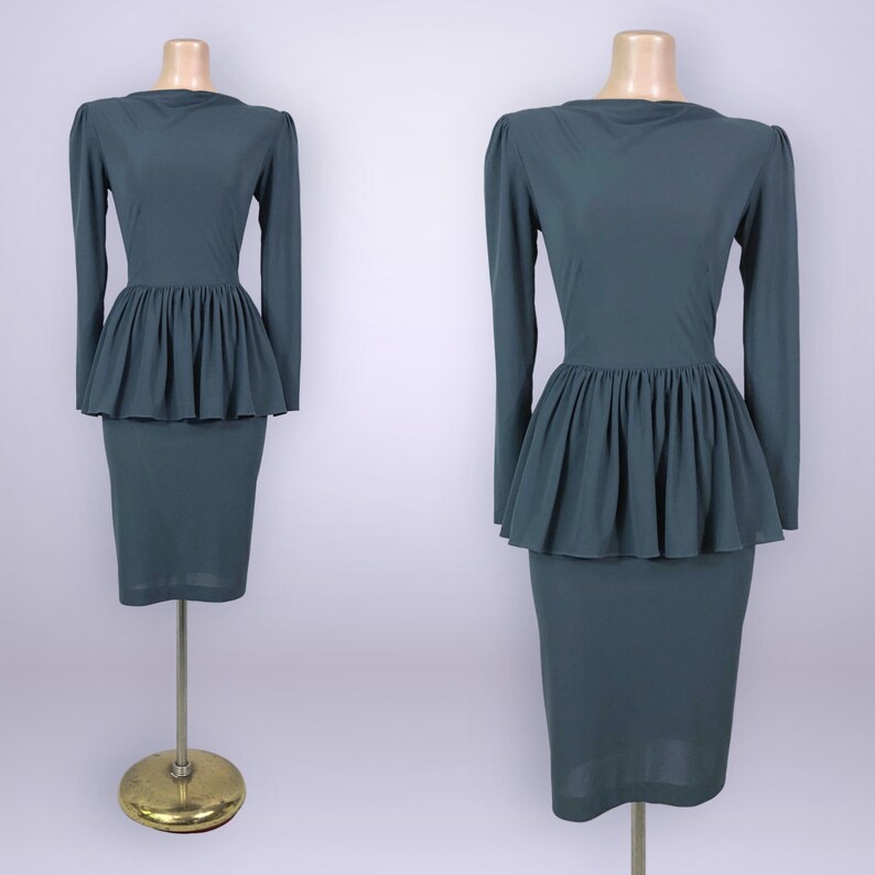 Puede incluir: Un vestido de color verde azulado con mangas largas y cintura peplum. El vestido se exhibe en un maniqu&iacute;. La falda es de estilo l&aacute;piz. El vestido est&aacute; hecho de una tela lisa y s&oacute;lida.