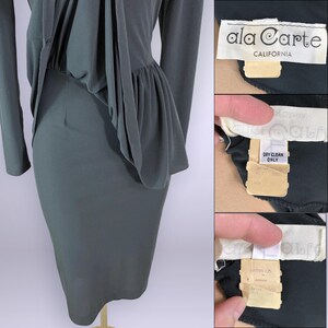 Puede incluir: Un vestido verde oscuro con mangas largas y un detalle de peplum en la cintura. El vestido tiene una falda ajustada y un corpi&ntilde;o drapeado. La etiqueta dice "ala Carte CALIFORNIA". El vestido est&aacute; hecho de una tela suave y fluida.