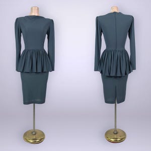 Puede incluir: Un vestido de color verde azulado con mangas largas y cintura peplum. El vestido tiene una falda l&aacute;piz ajustada y se muestra en un maniqu&iacute;. El vestido se muestra desde el frente y la espalda.