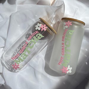 Könnte beinhalten: Zwei gefrostete Glaswasserflaschen mit rosa und grünen Blumenmustern und dem Text "Hot Girls Drink Matcha" und "Hot Girls Drink Matcha".