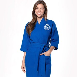 May include: A royal blue waffle weave robe with a white monogram on the left chest. The robe has a self-tie belt and two patch pockets.