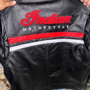 May include: Black leather motorcycle jacket with the embroidered words "Indian MOTORCYCLE" in red. The jacket has a red and white stripe design across the back.