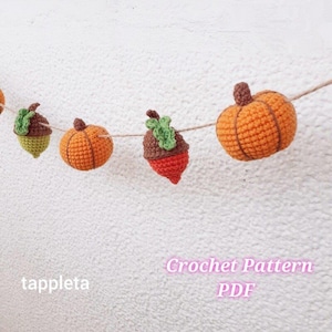 Pode incluir: Uma guirlanda de decorações de outono de crochê, incluindo abóboras laranja e bolotas com tampas marrons e folhas verdes, enfiadas em barbante. O texto "Crochet Pattern PDF" é visível na imagem.