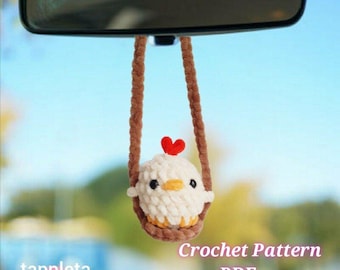 Peut inclure: Un charm de voiture en crochet représentant un poussin blanc avec un cœur rouge, suspendu à un rétroviseur. Le texte "Crochet Pattern PDF" et "tappleta" sont visibles. Un accessoire décoratif pour véhicule.