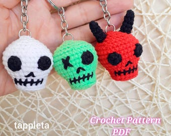 Puede incluir: Tres llaveros de calavera de ganchillo en blanco, verde y rojo, cada uno con detalles en negro. La calavera blanca tiene un diseño tradicional, la calavera verde tiene una "X" para un ojo y la calavera roja tiene cuernos. El texto en la imagen dice "Crochet Pattern PDF".