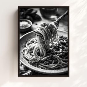 May include: Black and white photograph of a plate of spaghetti with sauce and grated cheese. A fork lifts a portion of the pasta, garnished with a basil leaf. The image is framed in a black border.