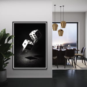 May include: Black and white framed art print featuring two dice in mid-air against a dark background. The dice are white with black dots, creating a high-contrast image. The artwork is displayed in a modern interior setting.