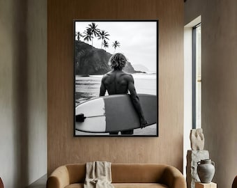 May include: A black and white framed wall art print depicting a person standing on a beach holding a surfboard. The scene features a rocky coastline with palm trees in the background, capturing a calm ocean view with a clear horizon line.
