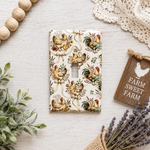 May include: A rectangular light switch cover plate featuring a repeating pattern of chickens, roosters, and small chicks interspersed with tan ribbons, sprigs of lavender, and small red berries against a cream-colored background.