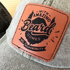 Peut inclure: Un patch en cuir marron avec des coutures noires et du texte qui dit "With Amazing Beard Comes Big Responsibility". Le patch est fix&eacute; &agrave; une casquette de baseball grise.