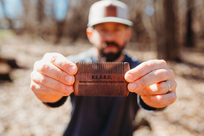 Peut inclure: Un peigne &agrave; barbe en bois avec le texte "B.E.A.R.D. Being Exceptional Among Regular Dudes" grav&eacute; sur le devant.
