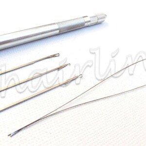 May include: A collection of hair extension tools, featuring a silver metal handle and multiple slender, silver needles with tiny hooks. Two long, curved silver wires are also visible. The tools are displayed on a white surface.