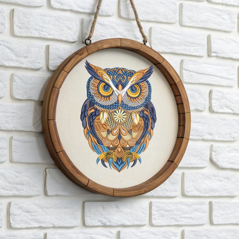 May include: Round wooden framed wall art featuring a detailed owl illustration. The owl is depicted with intricate patterns in shades of blue, orange, and yellow. The artwork is suspended by a natural rope.