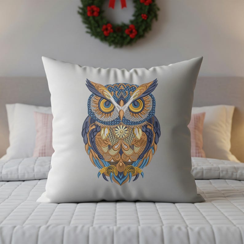 May include: White square pillow featuring a detailed owl design. The owl has intricate patterns in shades of blue, gold, and orange. The pillow is placed on a bed with a white comforter, with a Christmas wreath in the background.