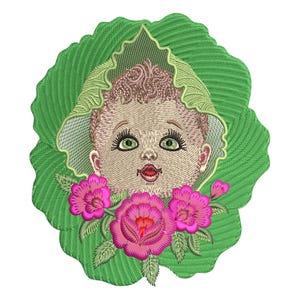 May include: Embroidered design featuring a baby's face with green eyes, framed by a green leaf and surrounded by pink flowers. The baby has light brown hair and a red mouth. The design is on a white background.