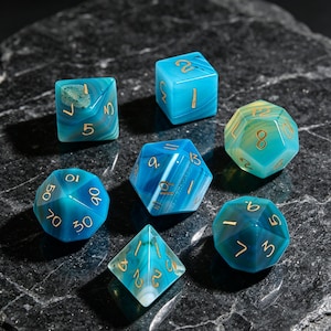 May include: A set of seven polyhedral dice crafted from blue and teal banded stone with gold-colored engraved numbers. The collection includes a d4, d6, d8, d10, d12, d20, and a percentile die, all featuring smooth, polished surfaces and distinct natural mineral patterns.