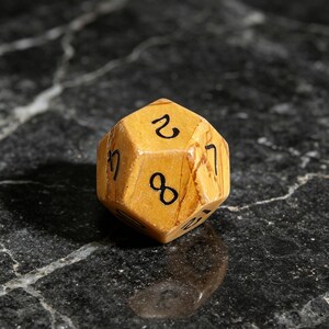 May include: A twenty-sided die crafted from tan and brown marbled stone. The die features black engraved numbers, including a prominent eight, a two, and a seven, distributed across its triangular faces with a smooth, polished finish.
