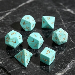 May include: A set of six polyhedral dice in a bright turquoise color with a marbled white vein pattern and engraved gold-colored numbers. The collection includes various geometric shapes used for tabletop gaming, featuring clear, legible numerals on each face.