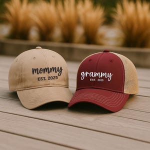 Pu&ograve; includere: Due cappellini da baseball. Uno &egrave; beige con la scritta "mommy" e "EST. 2025" ricamata in nero. L'altro &egrave; bordeaux con "grammy" e "EST. 2025" in bianco. Il secondo cappellino ha il retro in rete beige.