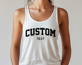 May include: White tank top with the word "CUSTOM" in bold black letters above the word "TEXT". The tank top has a scoop neck and is made of a soft material.