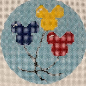 May include: A needlepoint canvas featuring a circular light blue background with three mouse-shaped balloons in dark blue, yellow, and red. Each balloon has a small white highlight, and they are connected by black stitched strings at the bottom.