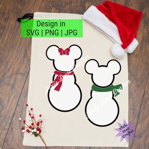 May include: A white canvas tote bag with the text "Design in SVG | PNG | JPG" printed in green. The bag features two snowman designs with Mickey Mouse ears and red and green scarves. A red Santa hat is on top of the bag.
