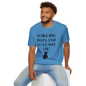May include: A light blue t-shirt with the text "I LIKE BIG POTS AND I CAN NOT LIE" in black, along with a black vase graphic. The shirt is worn by a person in blue jeans.