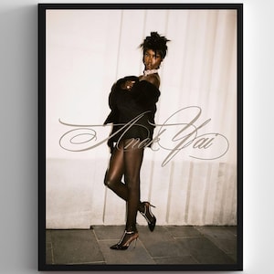 May include: A framed sepia-toned photograph featuring a person in a black outfit, high heels, and a diamond necklace. The image has the cursive text "Anek Yai" overlaid on the front.