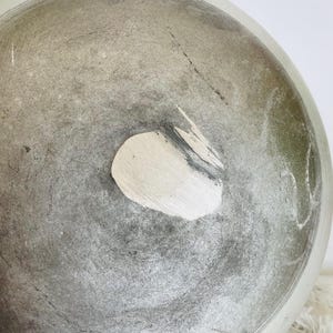 Puede incluir: Un taz&oacute;n grande, redondo, de cer&aacute;mica gris con una mancha blanca en el fondo. El taz&oacute;n tiene una superficie rugosa y texturizada.