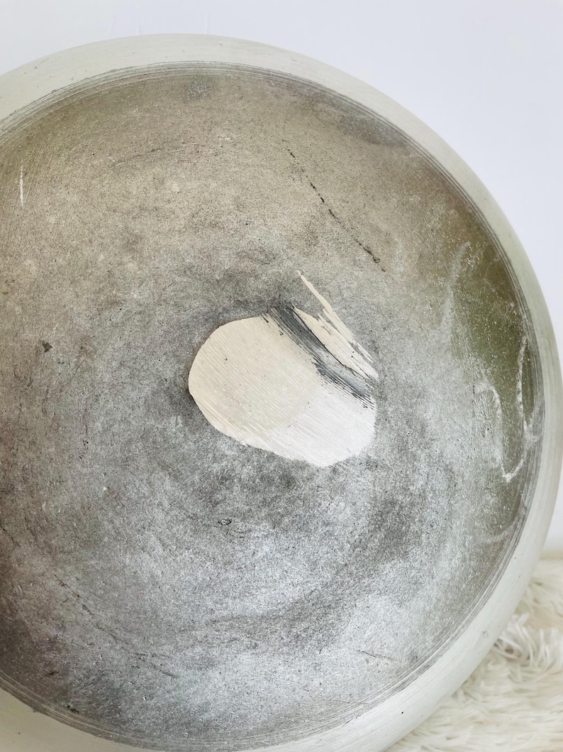 Puede incluir: Un taz&oacute;n grande, redondo, de cer&aacute;mica gris con una mancha blanca en el fondo. El taz&oacute;n tiene una superficie rugosa y texturizada.