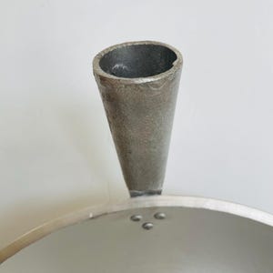 Puede incluir: Una olla de aluminio plateada con un mango de pico &uacute;nico. La olla tiene una superficie lisa y brillante y una base ancha y redonda.