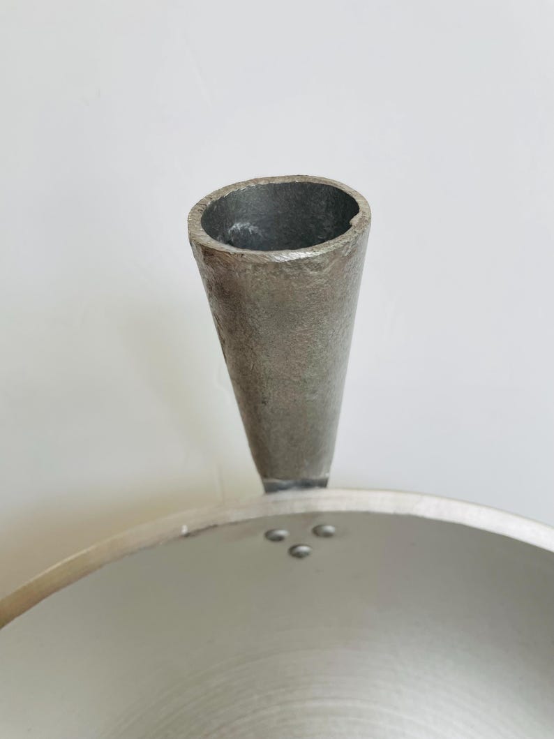 Puede incluir: Una olla de aluminio plateada con un mango de pico &uacute;nico. La olla tiene una superficie lisa y brillante y una base ancha y redonda.