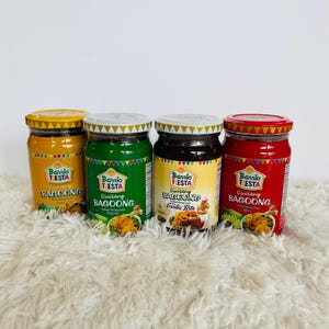 May include: Four glass jars of Barrio Fiesta Ginisang Bagoong, a Filipino fermented shrimp paste. The jars are labeled with the brand name, product name, and flavor variations: Regular, Garlic Bits, and Spicy.