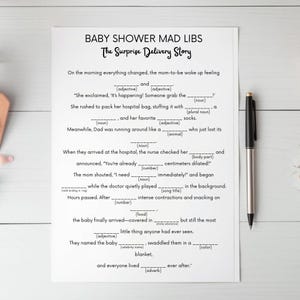 May include: A white Baby Shower Mad Libs game sheet with black text. The title reads "BABY SHOWER MAD LIBS The Surprise Delivery Story". The sheet has fill-in-the-blank sections for a fun baby shower activity. A black pen rests on the right side.