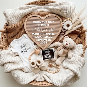 Puede incluir: Un tablero de letras en forma de corazón con texto, un body blanco con "Baby Williams", un osito de peluche, zapatos de bebé y una imagen de ultrasonido, todo en una cesta tejida. El tablero dice "WHEN THE TIME IS RIGHT, I. The Lord Will MAKE IT HAPPEN. ISAIAH 60:22 SEPTEMBER 2026."