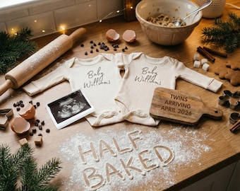 May include: A heartwarming scene featuring two cream-colored baby onesies with "Baby Williams" printed on them, an ultrasound image, and a wooden cutting board that reads "Twins Arriving April 2026". The words "HALF BAKED" are written in flour.