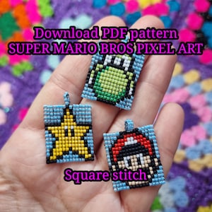 May include: Three square pixel art pendants featuring Super Mario Bros characters. Each pendant is made with small, colorful beads and has a blue border. The pendants include a star, a frog, and Mario. Text on the image reads "Download PDF pattern SUPER MARIO BROS PIXEL ART" and "Square stitch."