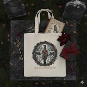 May include: Cream tote bag featuring a gothic illustration of a skeleton in a red coat, surrounded by dancers and trees. The bag contains books, a gift box with a red ribbon, and a decorative key. The text "GOTHIC CHRISTMAS DREAMS" is printed on the bag.