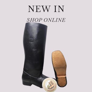 May include: A tall black leather boot with a smooth finish and a low heel, shown alongside its tan-coloured sole featuring a textured grip pattern. The text NEW IN and SHOP ONLINE appears above the boot, and a circular logo is at the bottom.