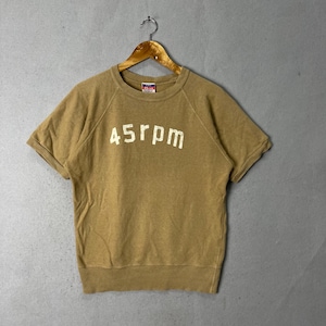 May include: A short-sleeved, tan-colored sweatshirt with the text "45rpm" in white block letters across the chest. The shirt is hanging on a wooden hanger against a neutral background. The shirt has a vintage or retro style.