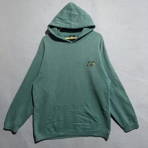 May include: A teal green hoodie with a hood and a front pocket. The hoodie has a small embroidered logo on the chest. The garment is made of a soft material and is suitable for casual wear.