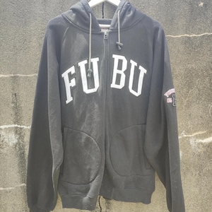 May include: Black zip-up hoodie with the white text "FU BU" across the chest. The hoodie has a drawstring hood, two front pockets, and a small patch on the sleeve. The hoodie is hanging on a white hanger.